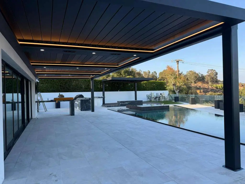 Wide poolside view of the 40 ft Monster Tank louvred patio with warm perimeter and recessed lights illuminated